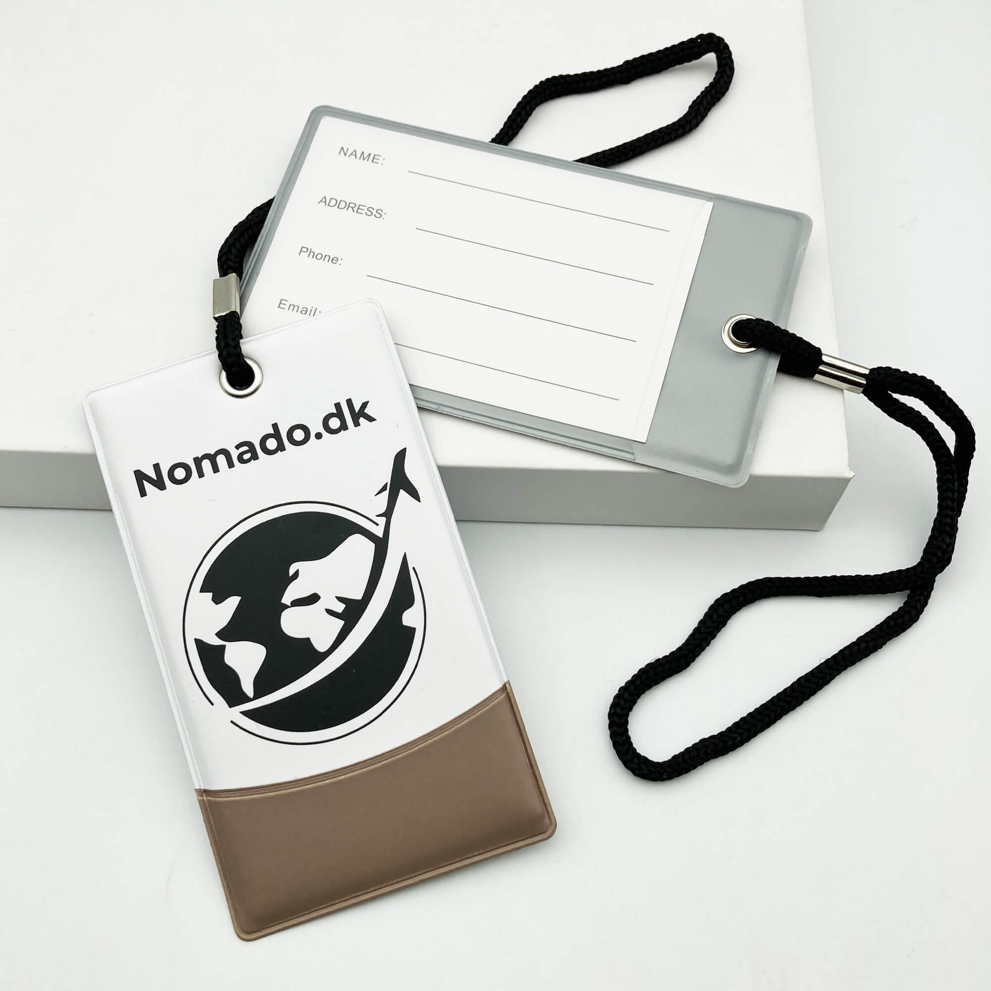Nomado kuffertmærker: Blå mærke med logo, grå med kontaktinfo